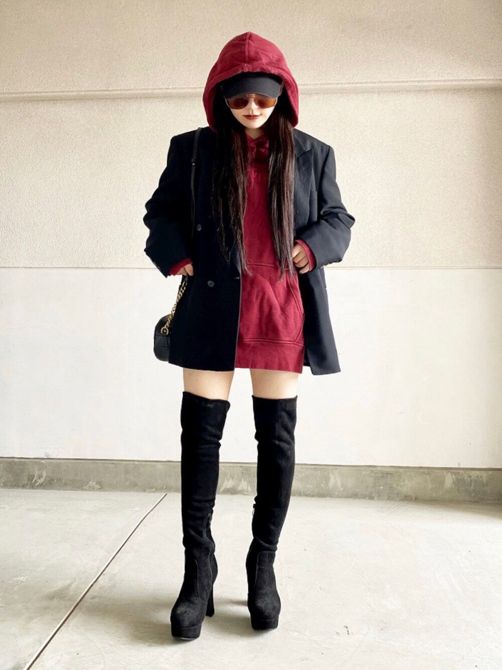 ブルー系のテーラードジャケット、レッド系のパーカー、ブラック系のブーツを着用したレディースの冬コーディネートの2枚目の写真