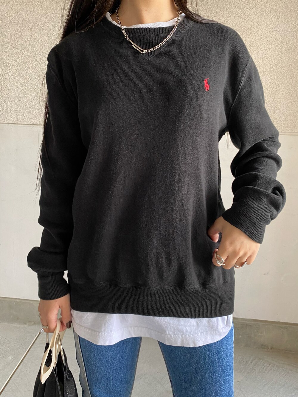 ブラック系のTシャツ/カットソー、ブラック系のハンドバッグ、ブルー系のデニムパンツを着用したレディースの冬コーディネートの2枚目の写真