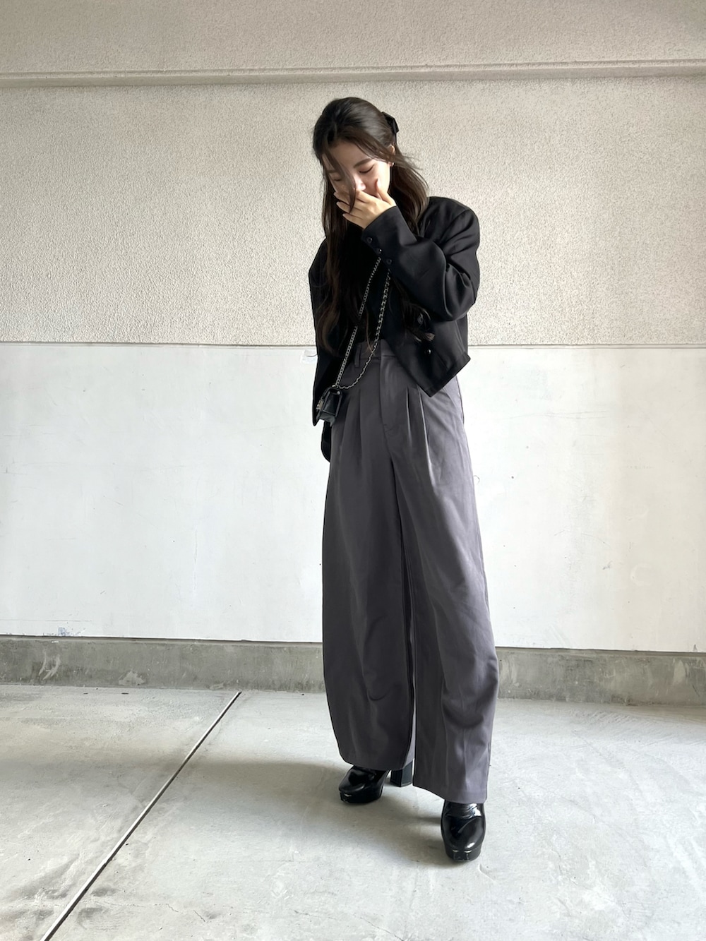 グレー系のパンツ、ブラック系のテーラードジャケット、ブラック系のブーツを着用したレディースの秋コーディネートの4枚目の写真