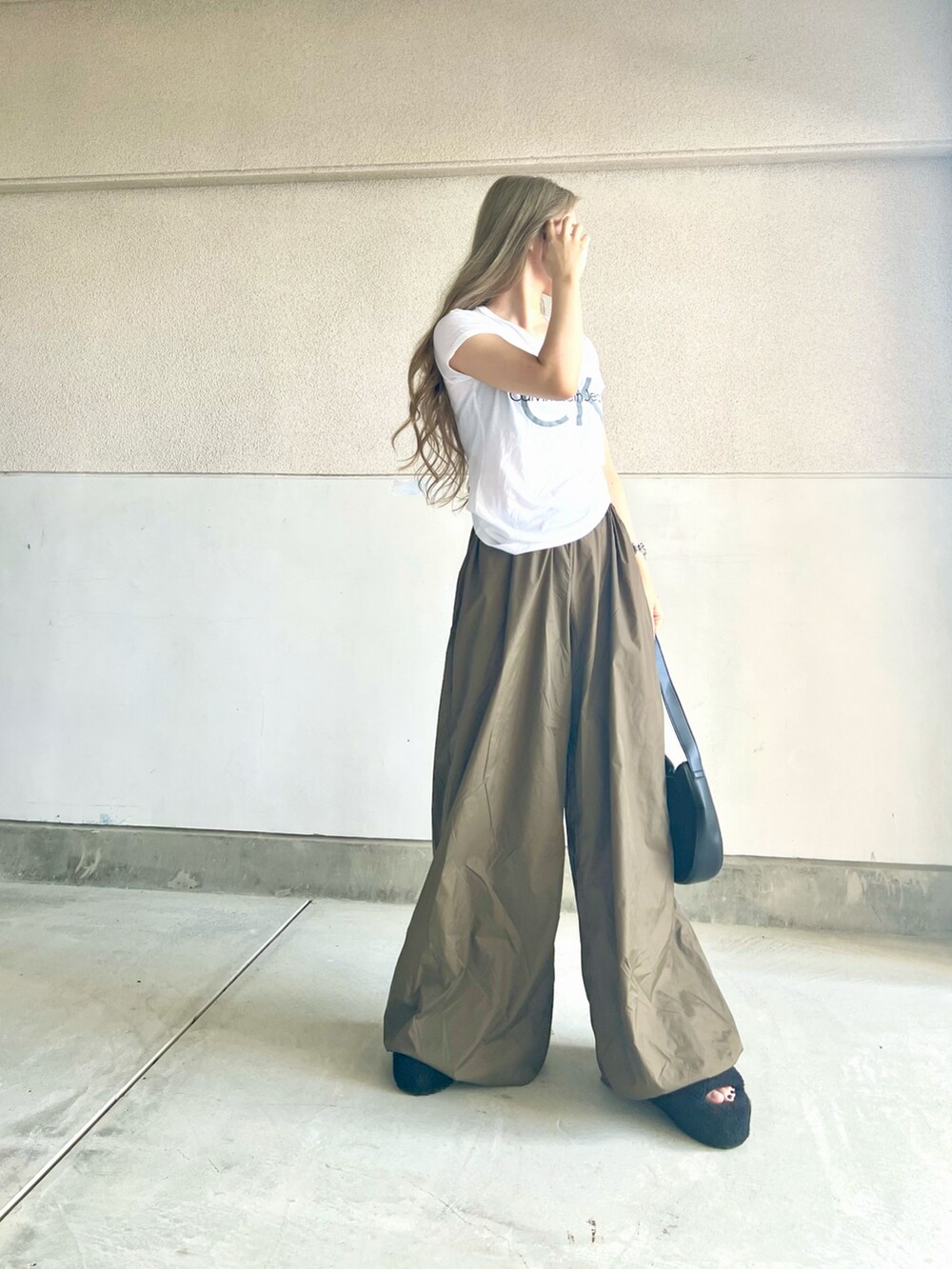 ブラック系のバッグ、ホワイト系のTシャツ/カットソー、グリーン系のパンツを着用したレディースの夏コーディネートの2枚目の写真