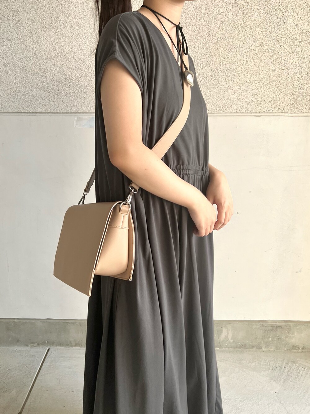 グレー系のワンピース、ベージュ系のショルダーバッグ、ブラック系のシューズを着用したレディースの夏コーディネートの5枚目の写真
