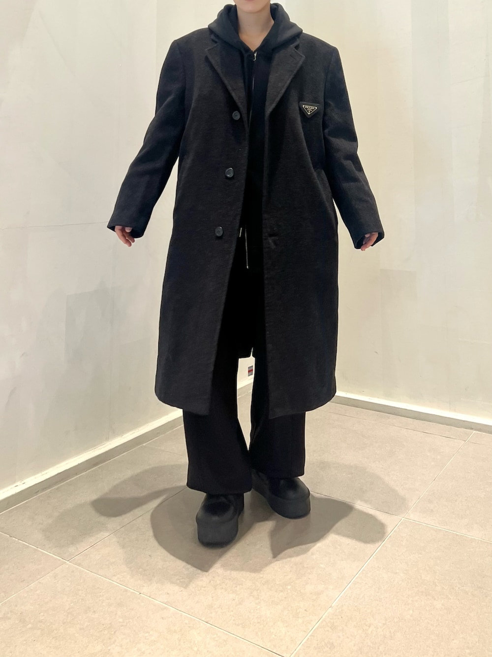 ブラック系のスウェットパンツ、ブラック系のパーカー、ブラック系のチェスターコートを着用したレディースの冬コーディネートの2枚目の写真