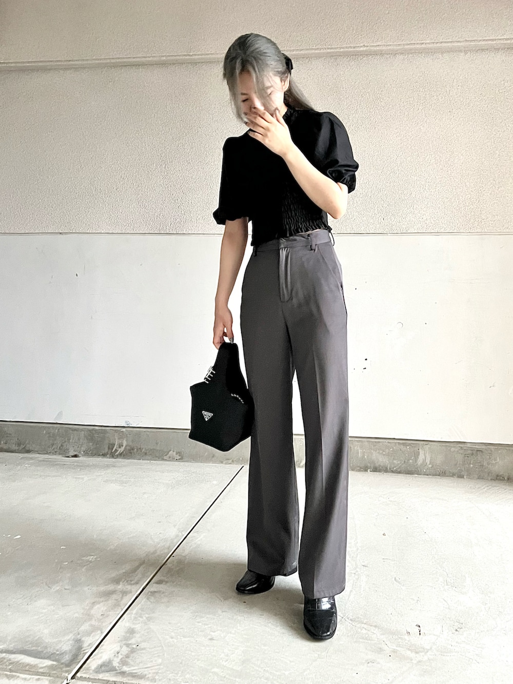 ブラック系のトップス、グレー系のパンツ、ブラック系のバッグを着用したレディースの夏コーディネートの2枚目の写真