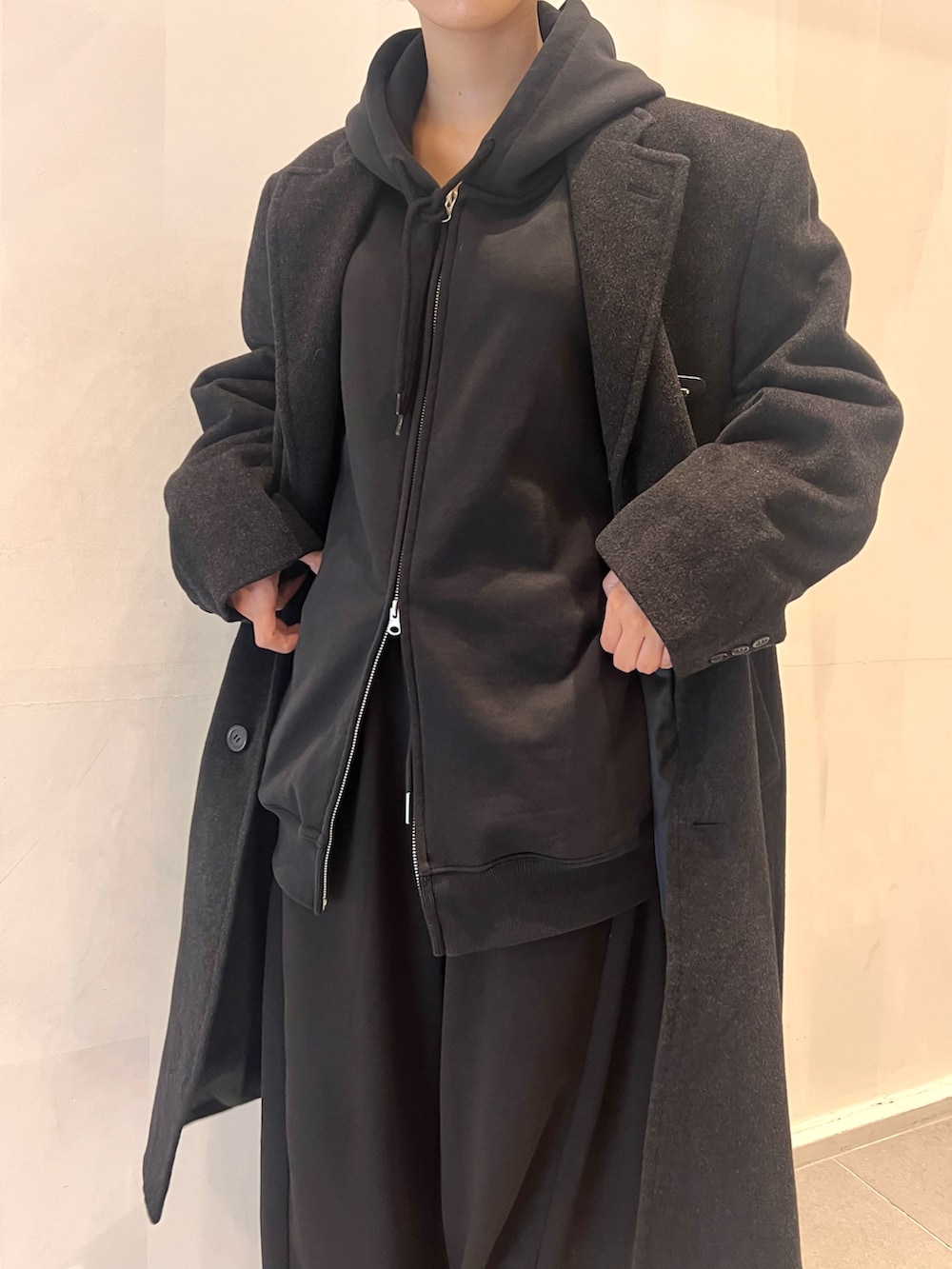 ブラック系のスウェットパンツ、ブラック系のパーカー、ブラック系のチェスターコートを着用したレディースの冬コーディネートの3枚目の写真