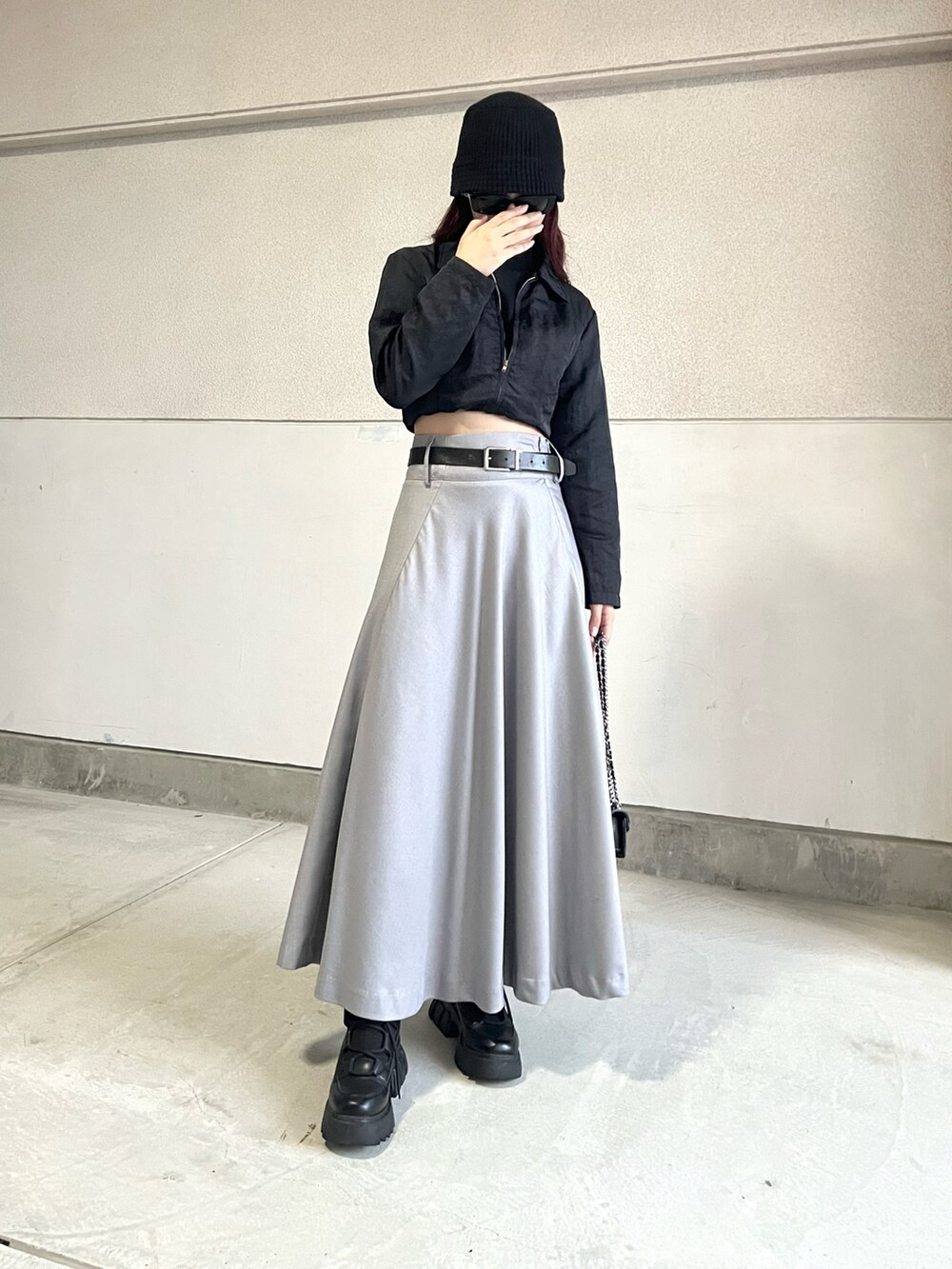 グレー系のスカート、ブラック系のブーツ、ブラック系のジャケット/アウターを着用したレディースの秋コーディネートの2枚目の写真