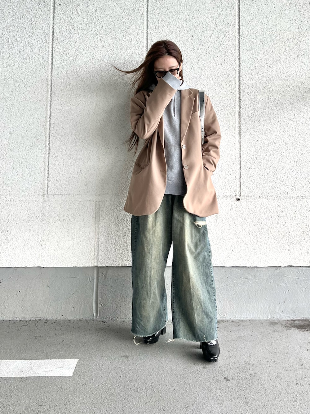 ブラウン系のテーラードジャケット、グレー系のパーカー、ブラック系のブーツを着用したレディースの冬コーディネートの4枚目の写真