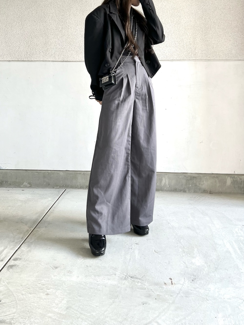 グレー系のパンツ、ブラック系のテーラードジャケット、ブラック系のブーツを着用したレディースの秋コーディネートの2枚目の写真