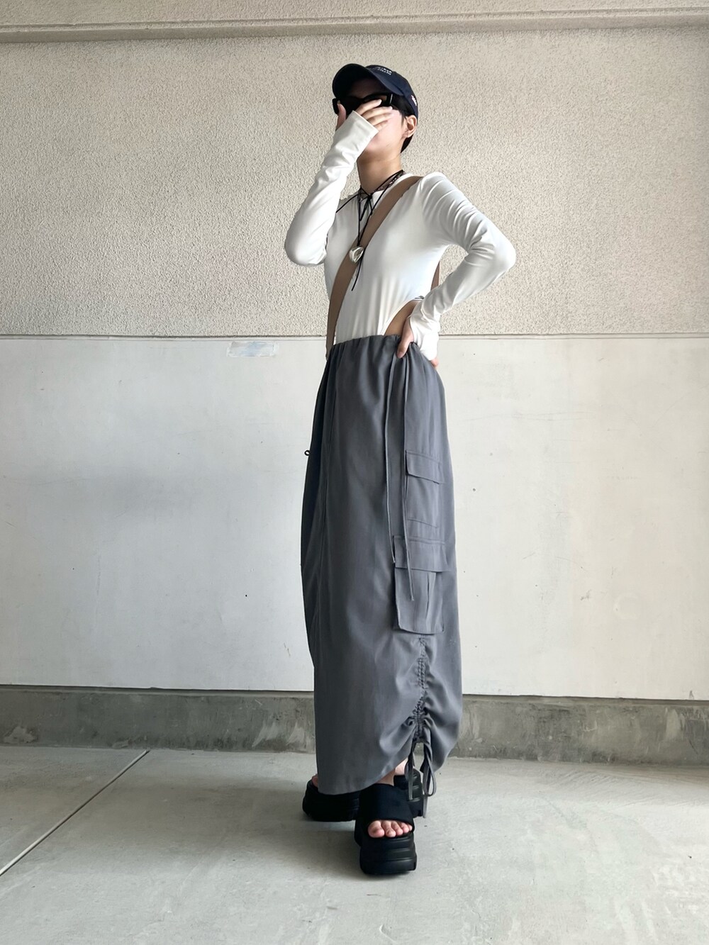 グレー系のスカート、ホワイト系のトップス、ベージュ系のショルダーバッグを着用したレディースの夏コーディネートの4枚目の写真