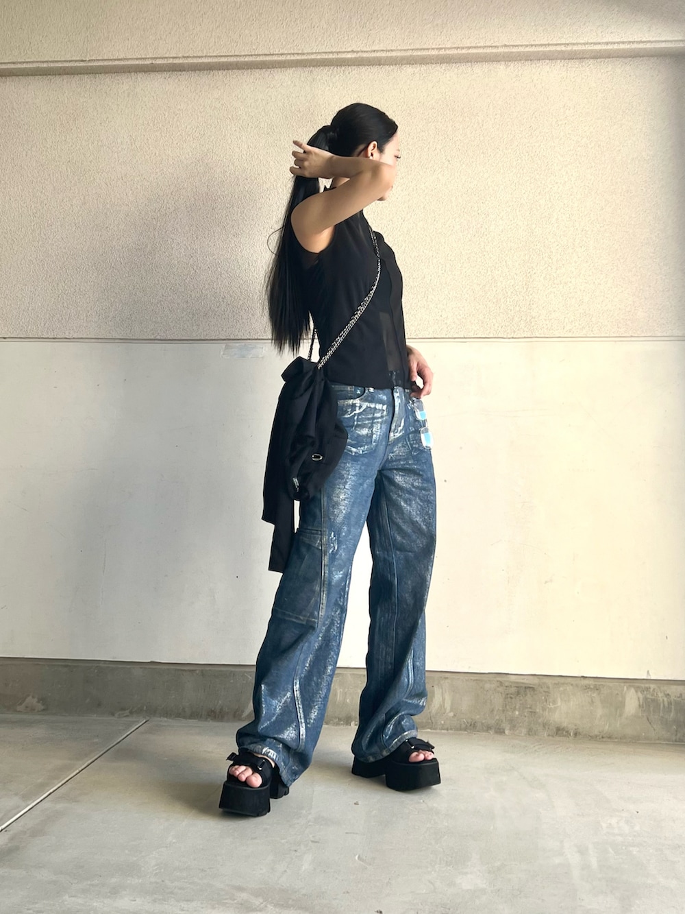 ブラック系のタンクトップ、ブルー系のデニムパンツ、ブラック系のサンダルを着用したレディースの夏コーディネートの4枚目の写真