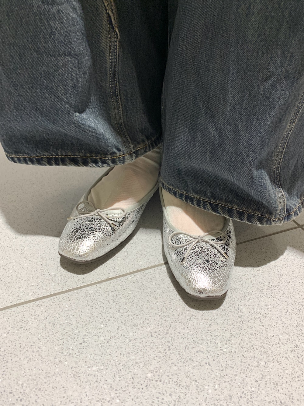 グリーン系のショルダーバッグ、ブルー系のデニムパンツ、グレー系のカーディガン/ボレロを着用したレディースの春コーディネートの2枚目の写真