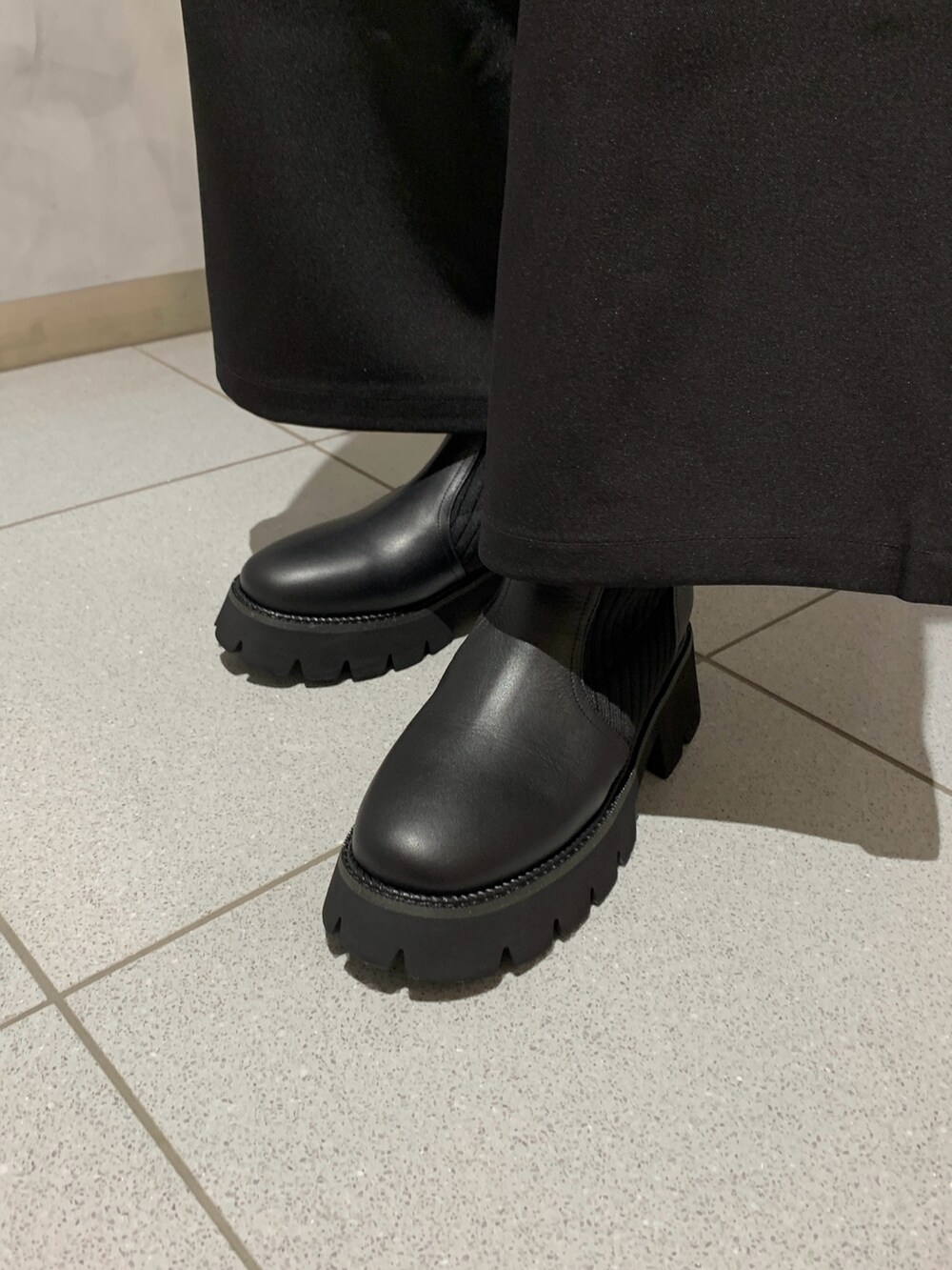 グレー系のニット/セーター、ブラック系のパンツ、ブラック系のブーツを着用したレディースの秋コーディネートの2枚目の写真