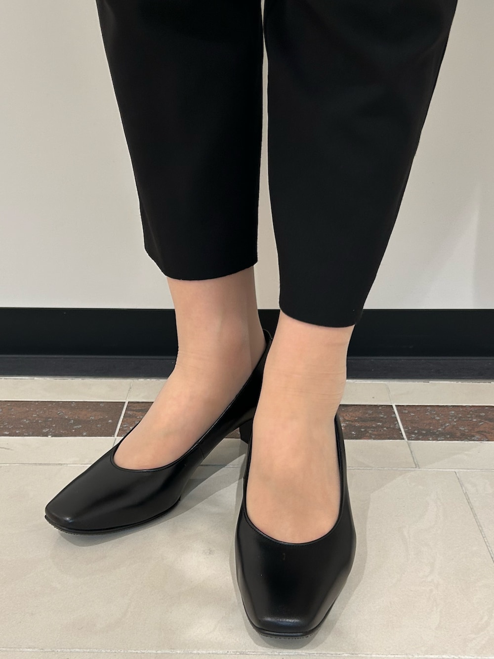 ブラック系のパンプス、ブラック系のショルダーバッグを着用したレディースの春コーディネートの2枚目の写真