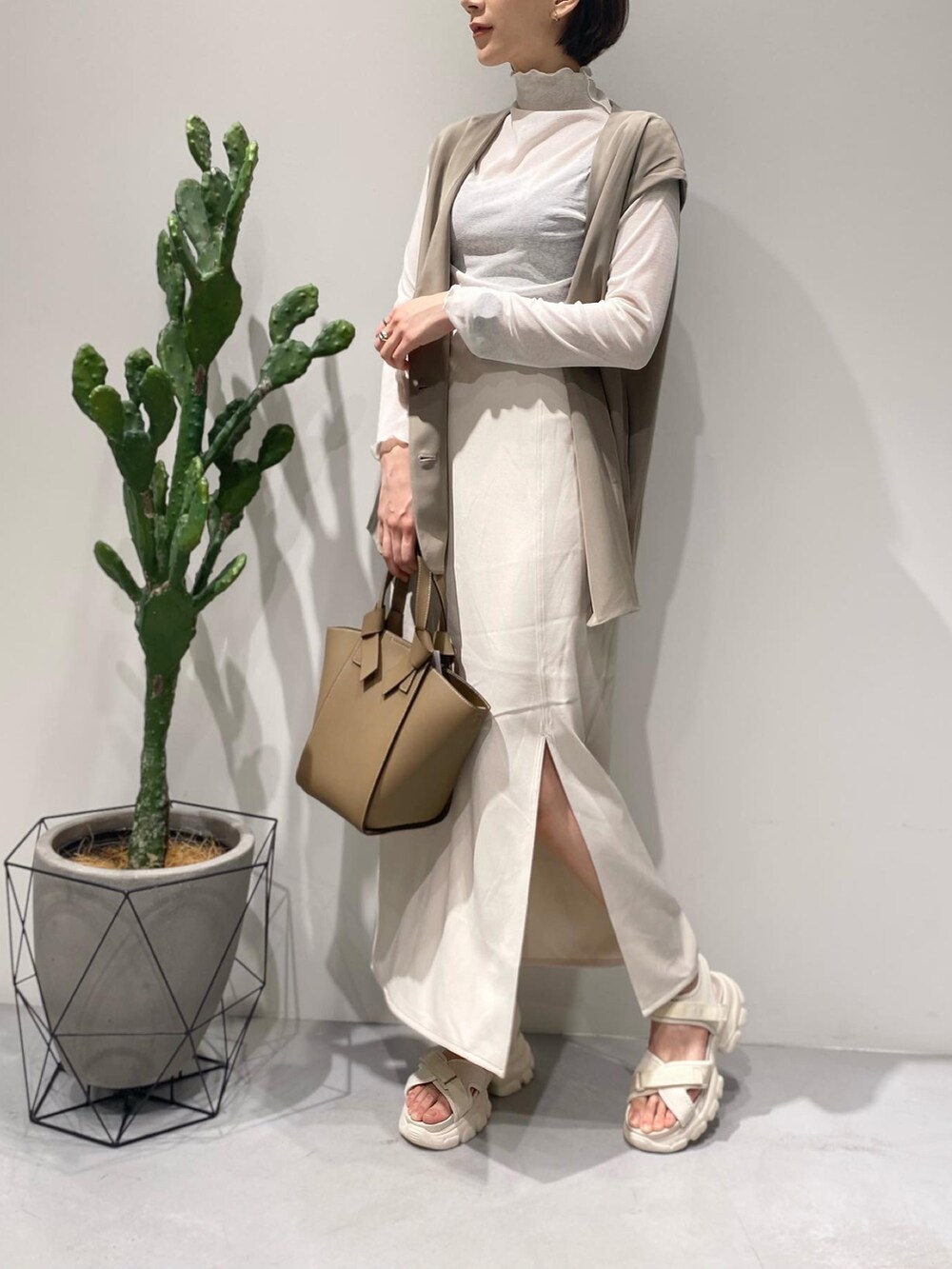 ホワイト系のTシャツ/カットソー、ホワイト系のスカート、ベージュ系のベストを着用したレディースの春コーディネートの2枚目の写真