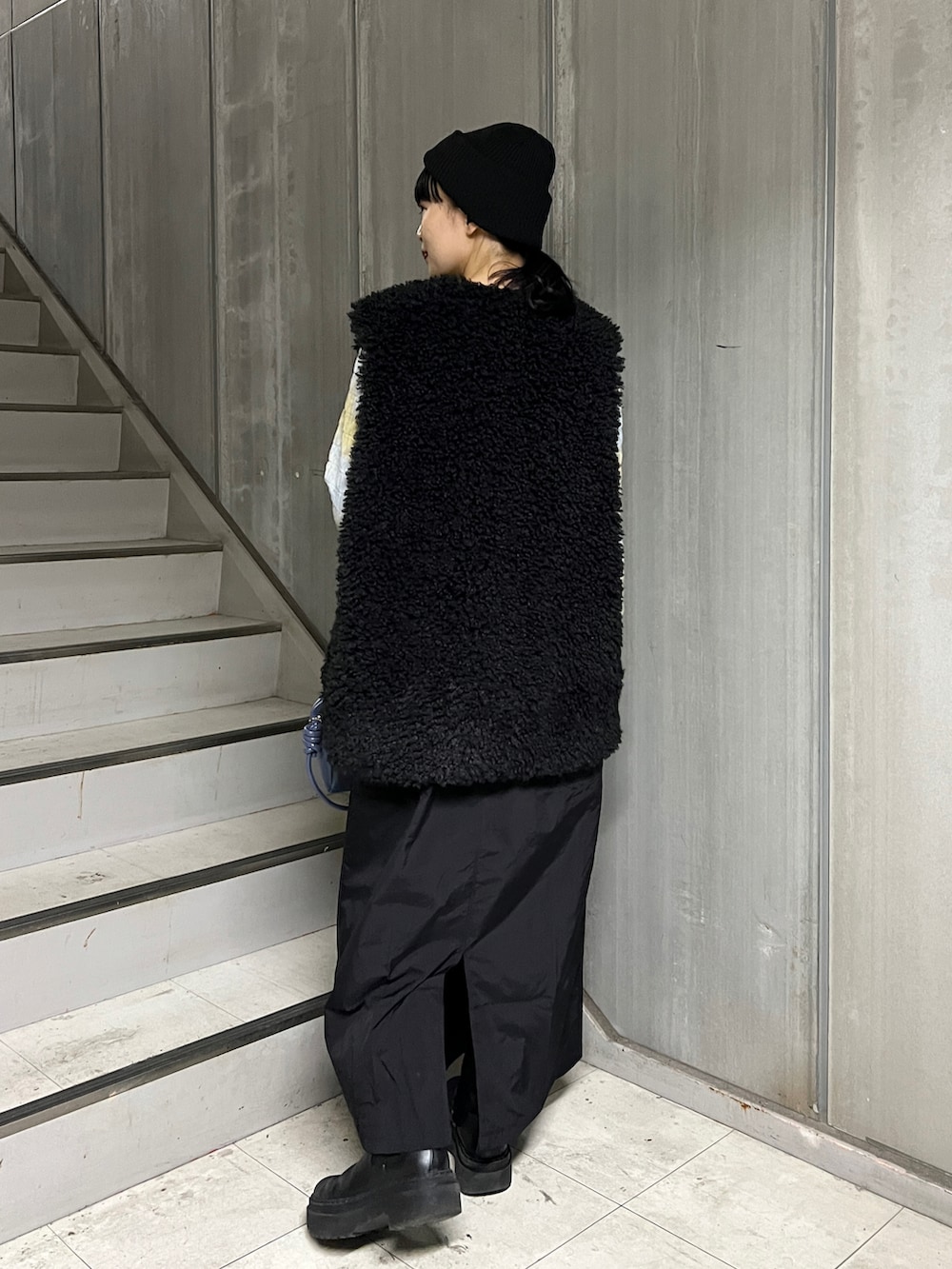 ブラック系のベスト、ブルー系のボストンバッグ、ブラック系のワンピースを着用したレディースの秋コーディネートの3枚目の写真