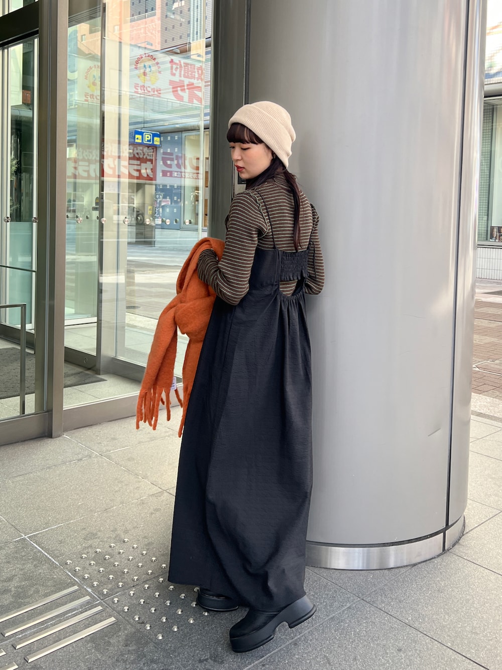 ブラック系のブーツ、ブラック系のワンピース、ブラウン系のニット/セーターを着用したレディースの冬コーディネートの2枚目の写真