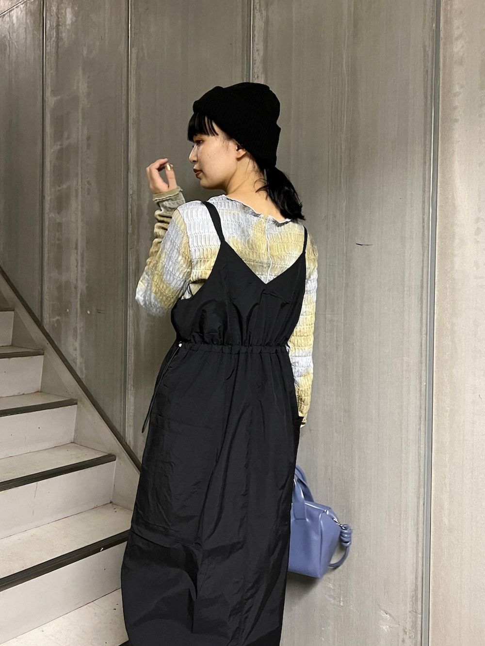 ブラック系のベスト、ブルー系のボストンバッグ、ブラック系のワンピースを着用したレディースの秋コーディネートの4枚目の写真