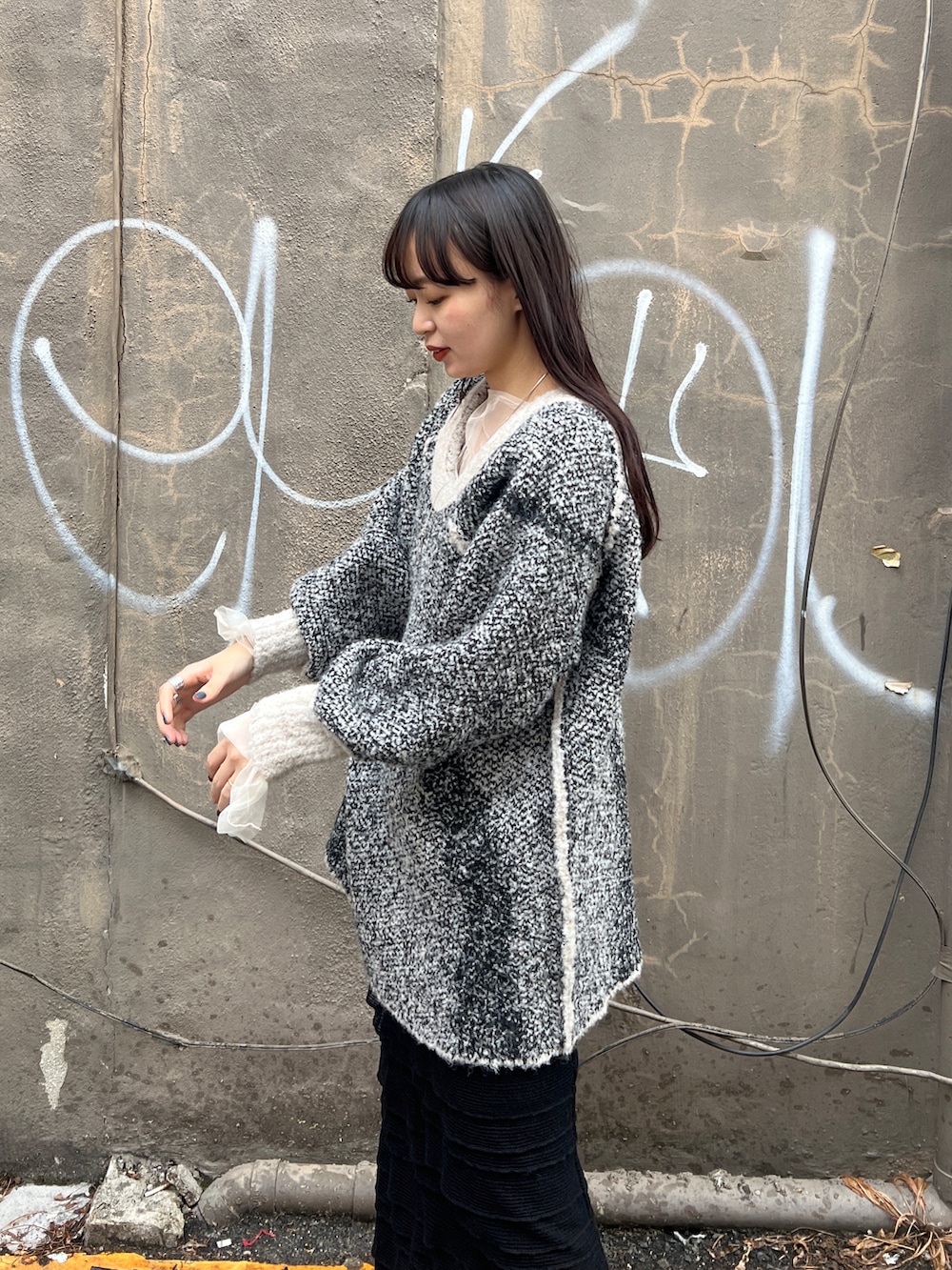 ブラック系のブーツ、ブラック系のスカート、ホワイト系のニット/セーターを着用したレディースの秋コーディネートの3枚目の写真