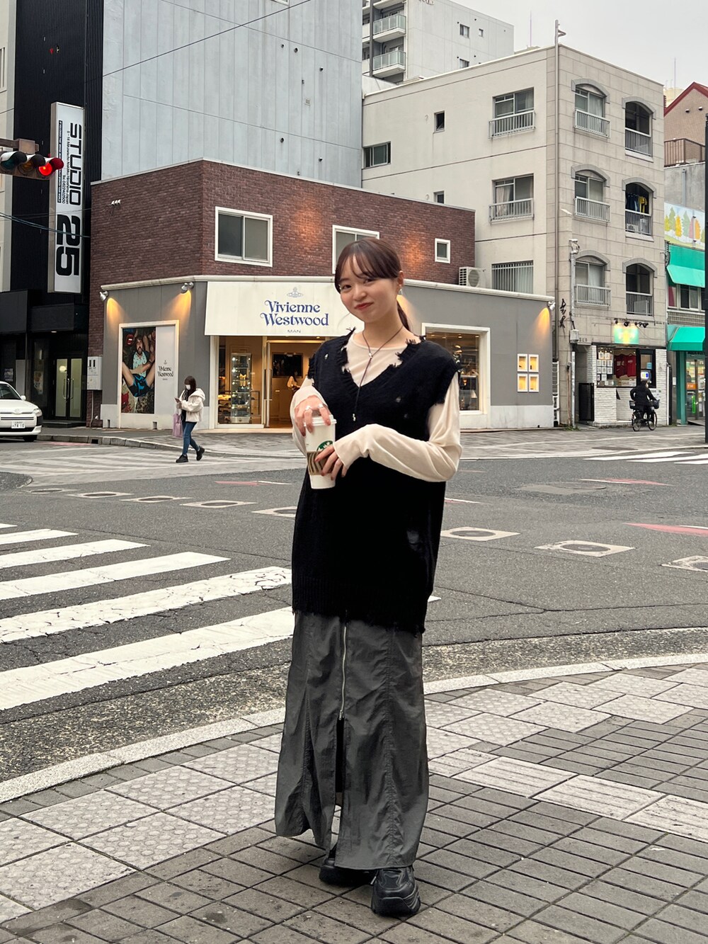 グレー系のスカート、ブラック系のベスト、ブラック系のスニーカーを着用したレディースの冬コーディネートの5枚目の写真