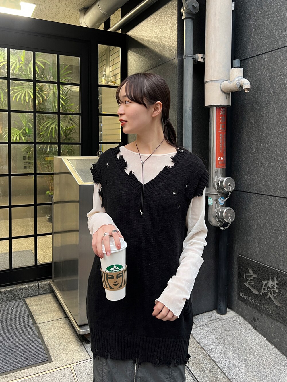 グレー系のスカート、ブラック系のベスト、ブラック系のスニーカーを着用したレディースの冬コーディネートの4枚目の写真