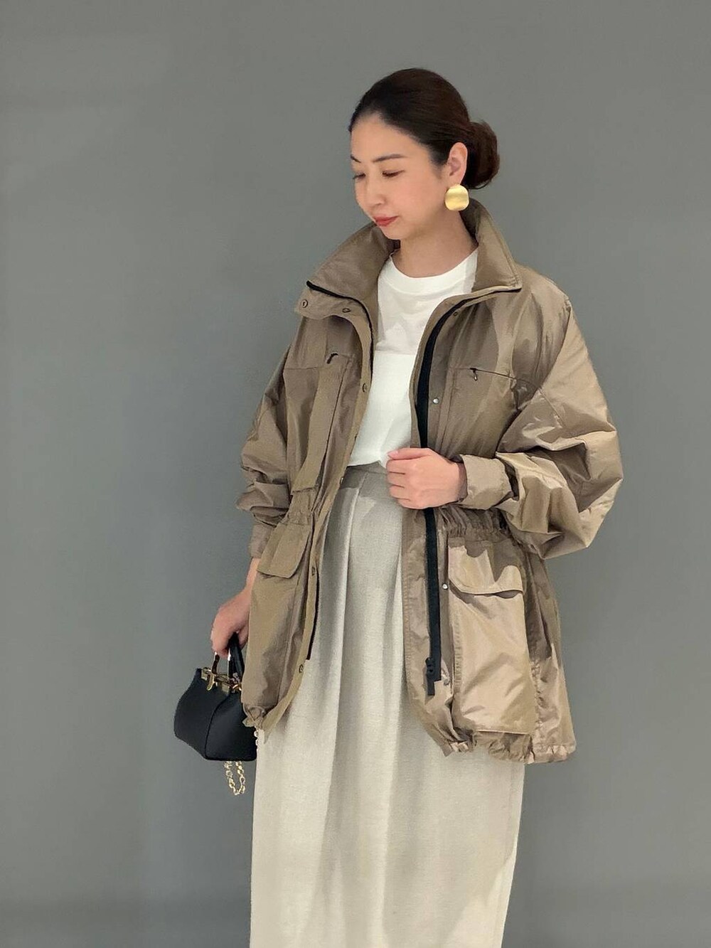 ホワイト系のスカート、ベージュ系のブルゾン、ホワイト系のTシャツ/カットソーを着用したレディースの春コーディネートの3枚目の写真