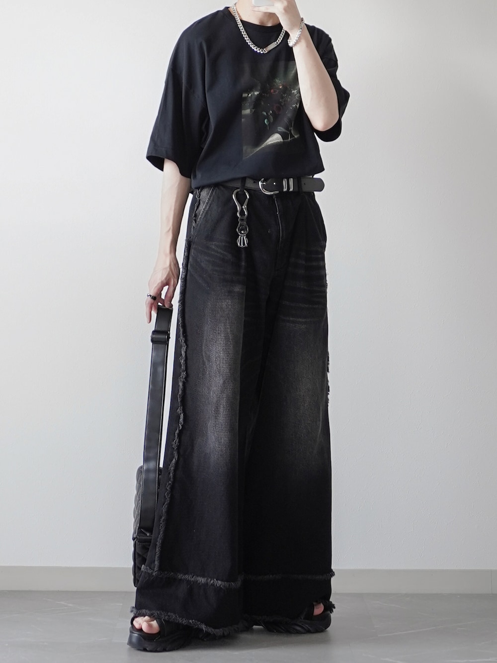 ブラック系のTシャツ/カットソー、ブラック系のデニムパンツ、ブラック系のサンダルを着用したメンズの夏コーディネートの3枚目の写真