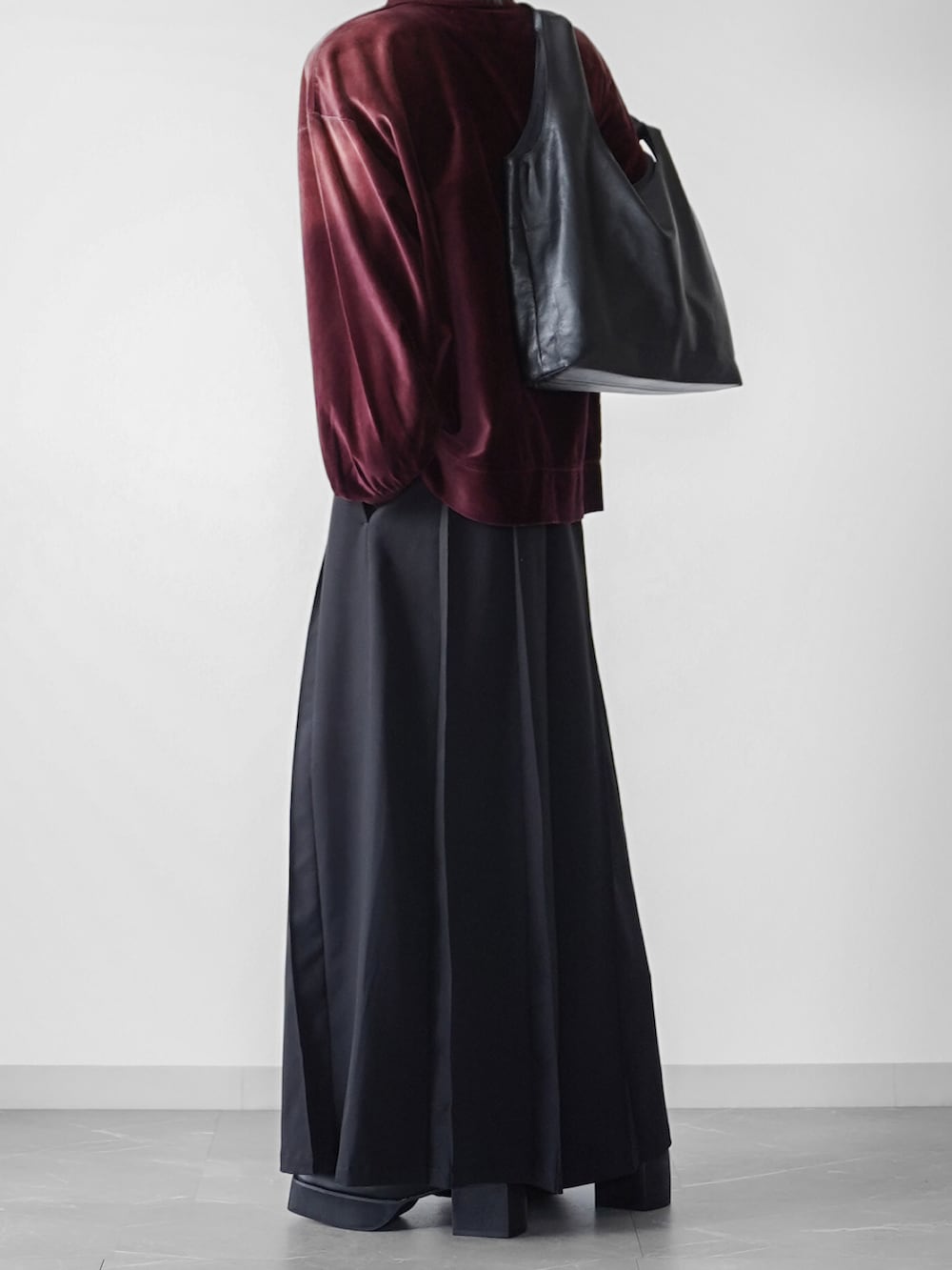 レッド系のスウェット、ブラック系のスラックス、ブラック系のトートバッグを着用したメンズの秋コーディネートの2枚目の写真