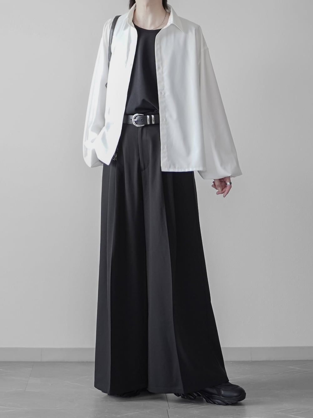 ホワイト系のタンクトップ、ブラック系のショルダーバッグ、ブラック系のスニーカーを着用したメンズの秋コーディネートの2枚目の写真