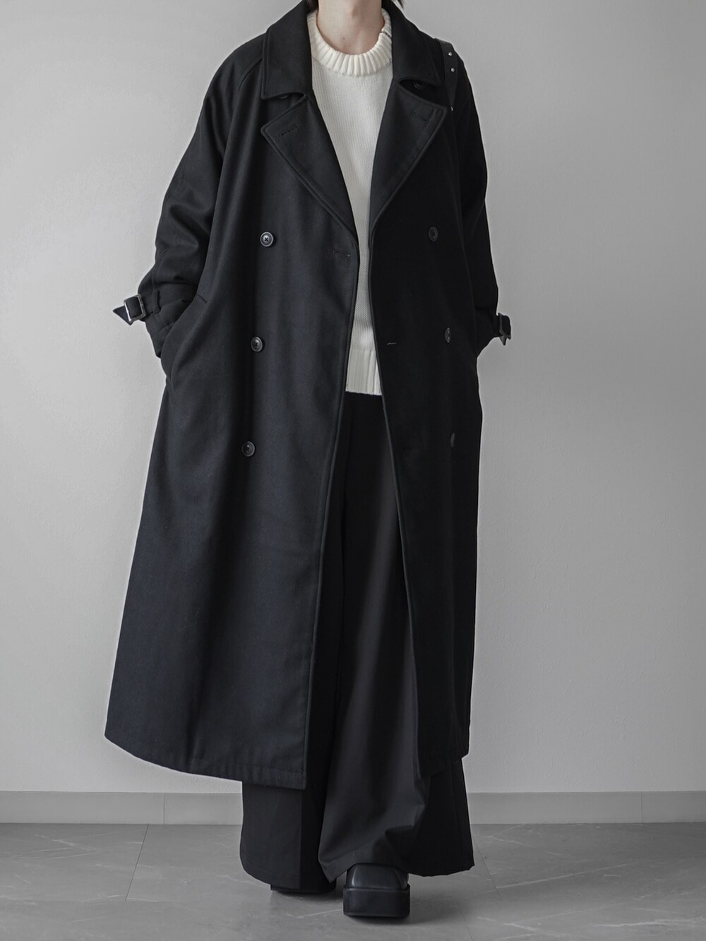 ブラック系のステンカラーコート、ブラック系のスラックス、ブラック系のブーツを着用したメンズの秋コーディネートの2枚目の写真