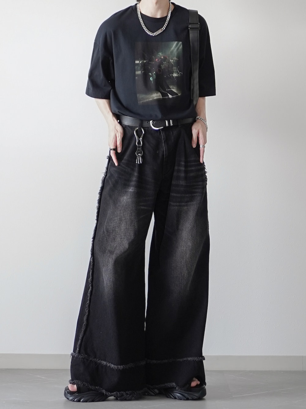 ブラック系のTシャツ/カットソー、ブラック系のデニムパンツ、ブラック系のサンダルを着用したメンズの夏コーディネートの2枚目の写真