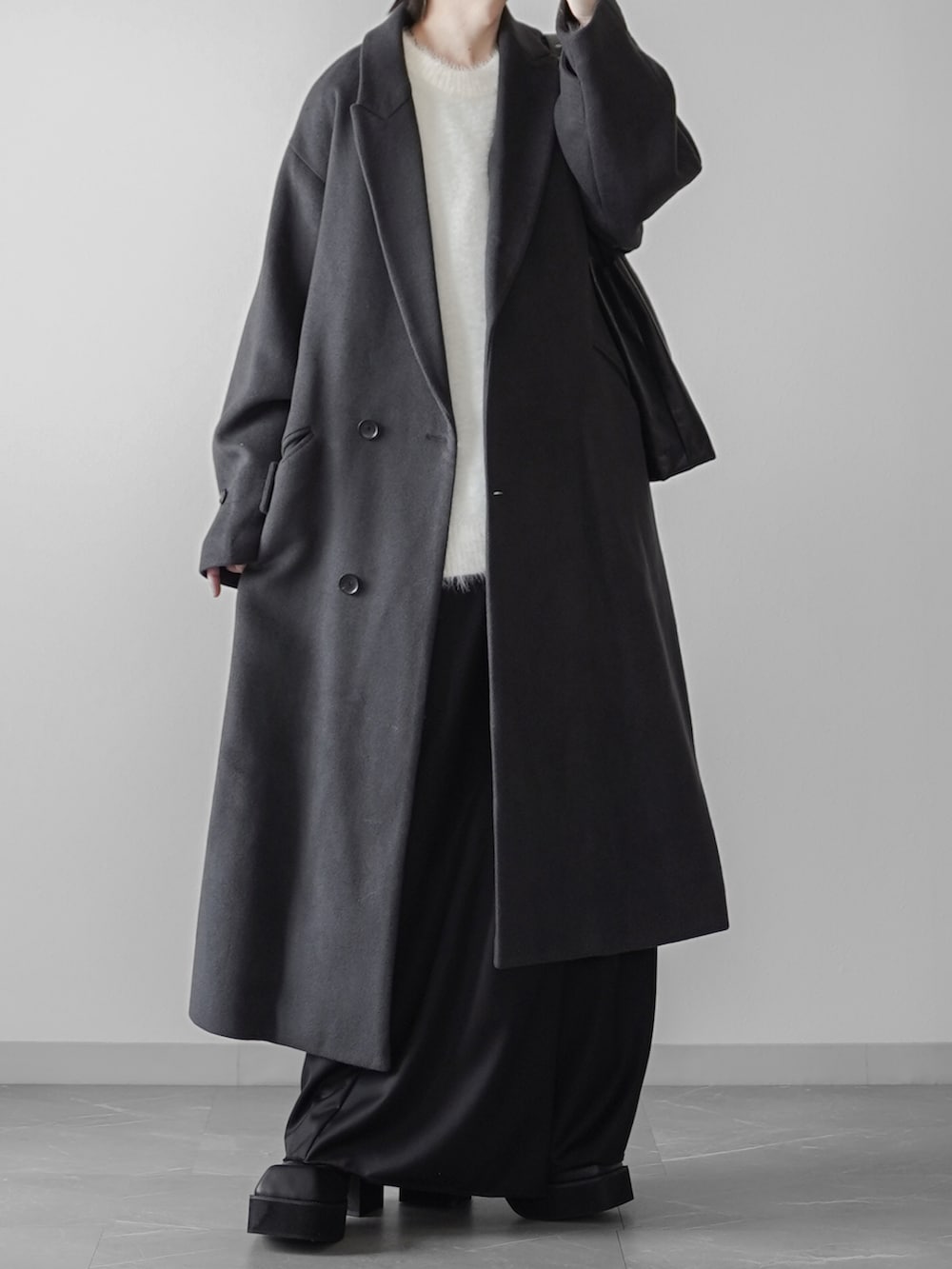 ホワイト系のニット/セーター、ブラック系のスラックス、グレー系のトレンチコートを着用したメンズの秋コーディネートの2枚目の写真