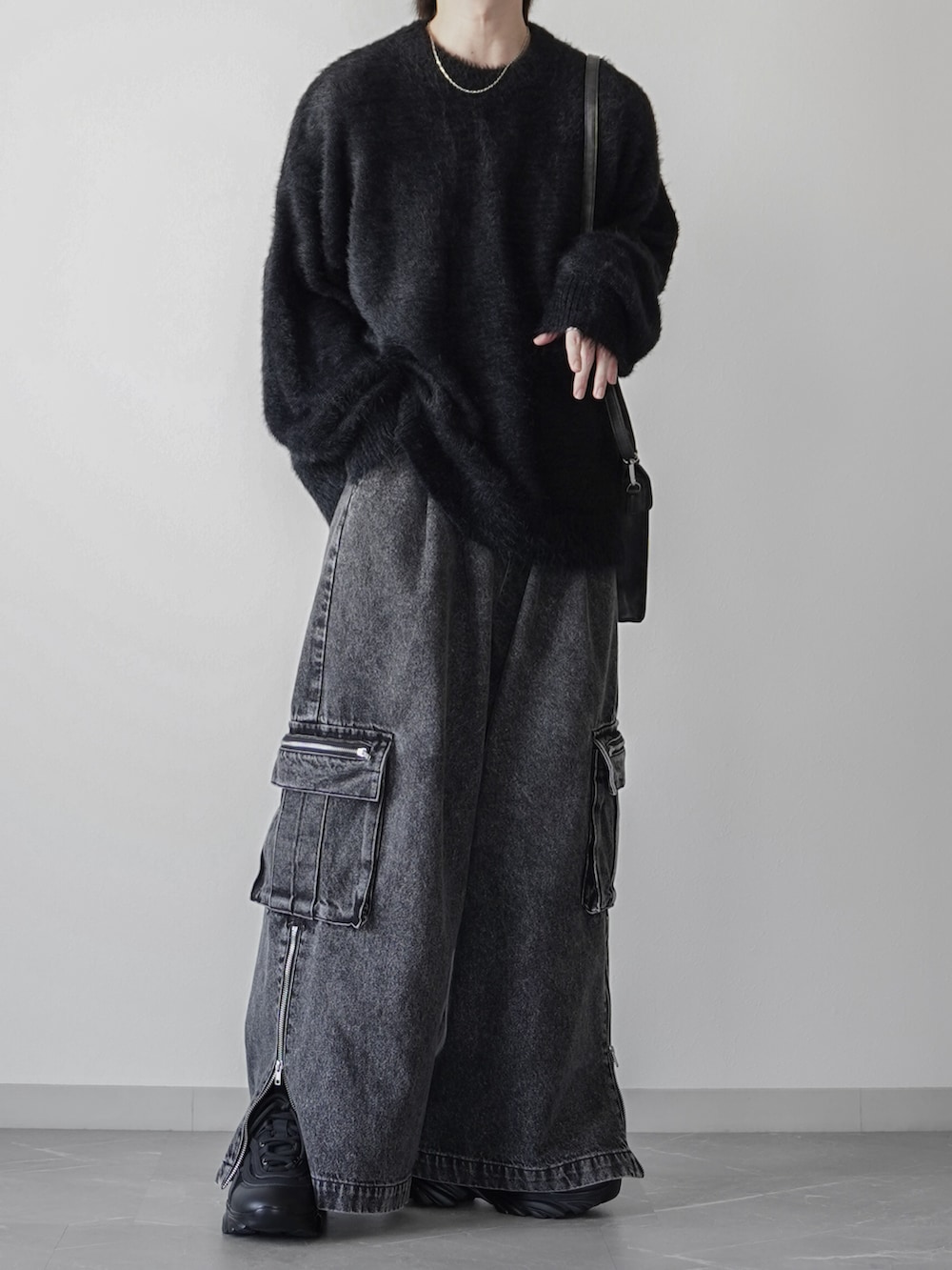 ブラック系のニット/セーター、ブラック系のカーゴパンツ、ブラック系のショルダーバッグを着用したメンズの秋コーディネートの3枚目の写真