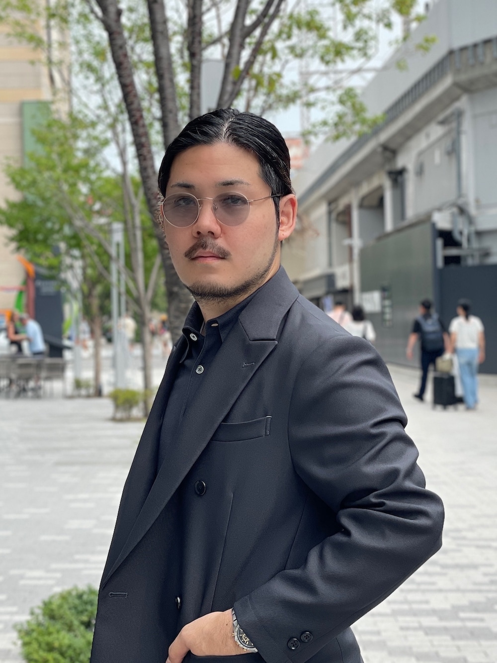 グレー系のスーツパンツ、グレー系のポロシャツ、ブラック系のドレスシューズを着用したメンズの秋コーディネートの4枚目の写真