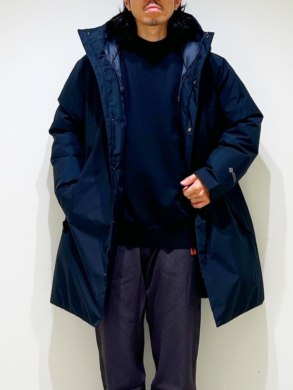 ブラック系のニット/セーター、ブラック系のダウンジャケット/コート、グレー系のスラックスを着用したメンズの秋コーディネートの9枚目の写真