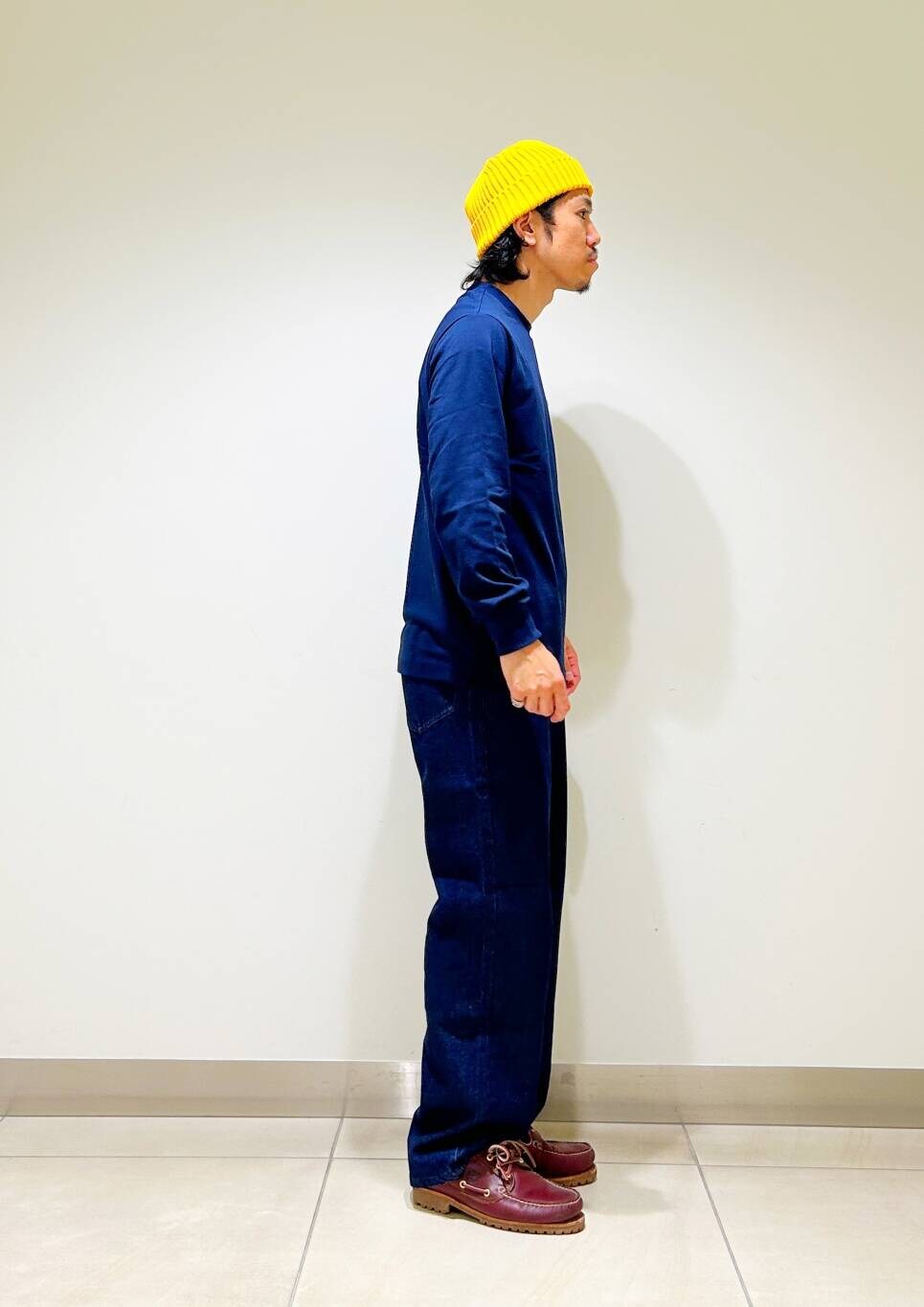 ブルー系のデニムパンツ、ブルー系のTシャツ/カットソー、イエロー系のニットキャップ/ビーニーを着用したメンズの秋コーディネートの6枚目の写真