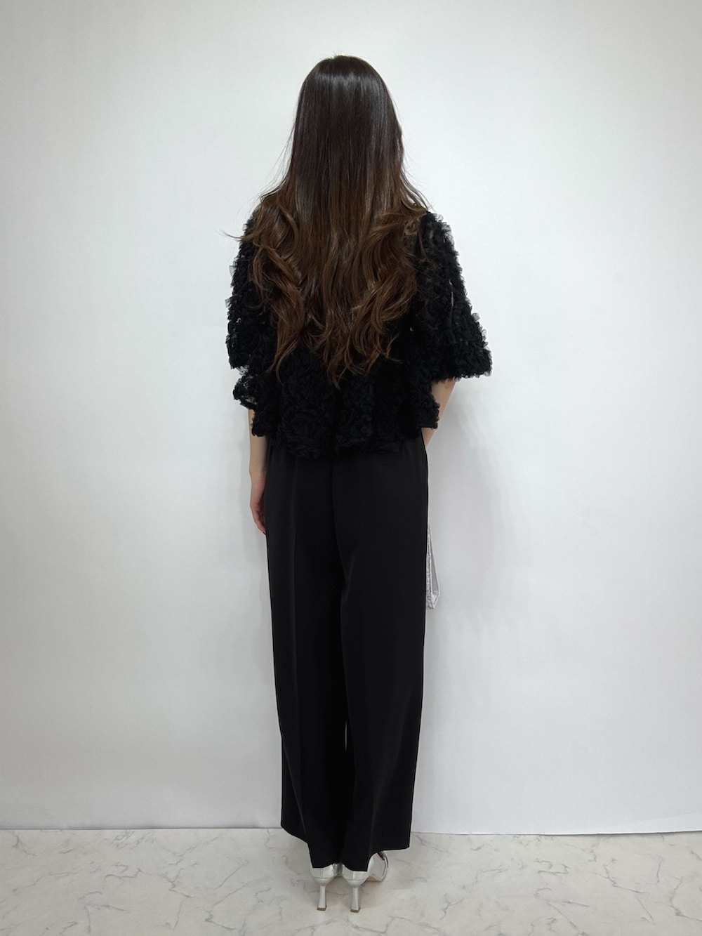 シルバー系のクラッチバッグ、シルバー系のパンプス、ブラック系のドレスを着用したレディースの秋コーディネートの3枚目の写真