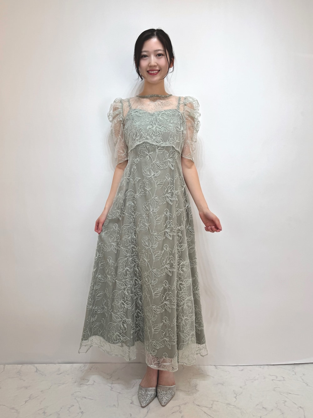 グリーン系のドレス、シルバー系のパンプスを着用したレディースの冬コーディネートの2枚目の写真