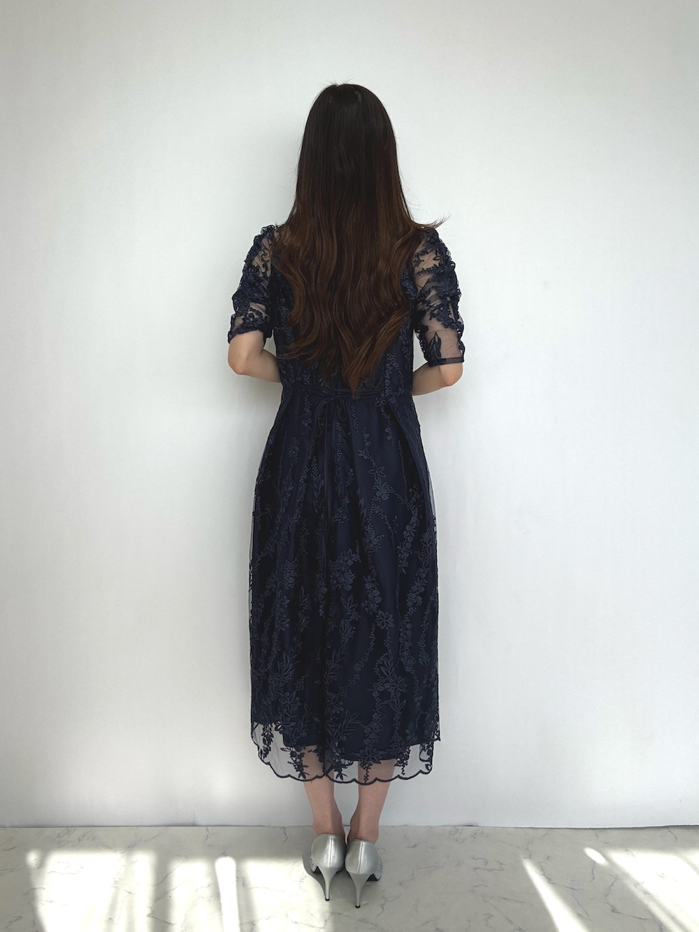 ブルー系のドレス、シルバー系のパンプス、シルバー系のクラッチバッグを着用したレディースの秋コーディネートの4枚目の写真