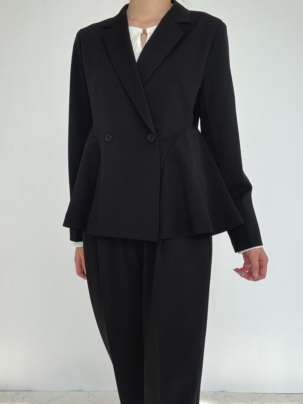 ブラック系のスーツセット、シルバー系のパンプスを着用したレディースの冬コーディネートの4枚目の写真