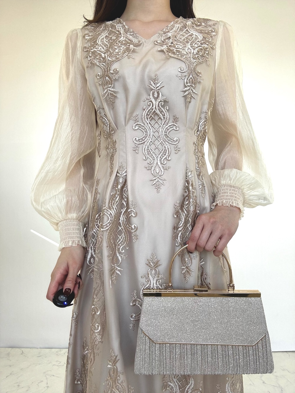 ベージュ系のドレス、ベージュ系のクラッチバッグ、ベージュ系のパンプスを着用したレディースの秋コーディネートの3枚目の写真