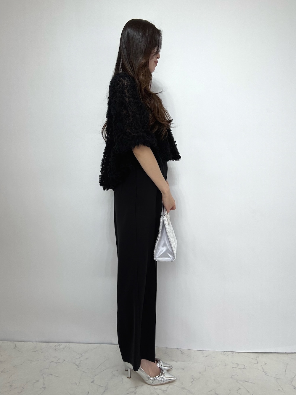 シルバー系のクラッチバッグ、シルバー系のパンプス、ブラック系のドレスを着用したレディースの秋コーディネートの2枚目の写真