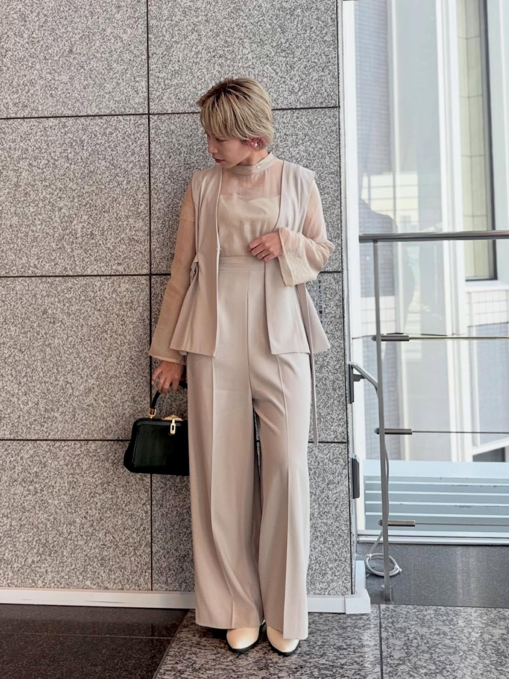 ベージュ系のスーツセットを着用したレディースの冬コーディネートの2枚目の写真