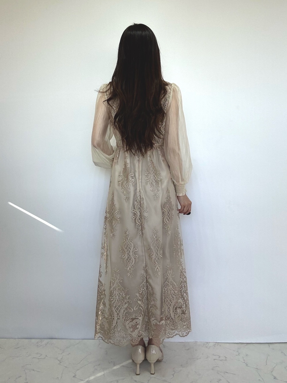 ベージュ系のドレス、ベージュ系のクラッチバッグ、ベージュ系のパンプスを着用したレディースの秋コーディネートの2枚目の写真