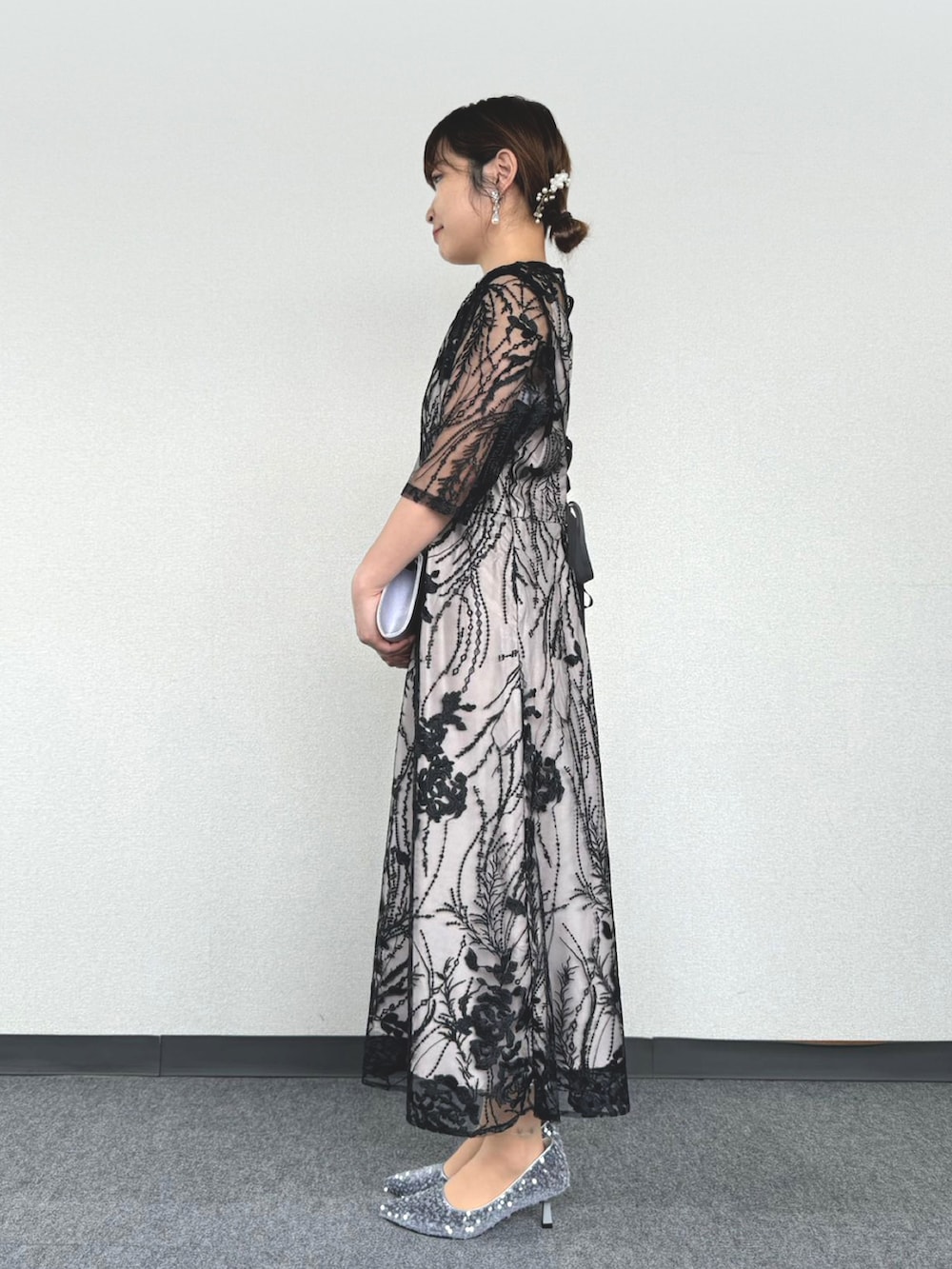 シルバー系のパンプス、ブラック系のドレスを着用したレディースの冬コーディネートの2枚目の写真