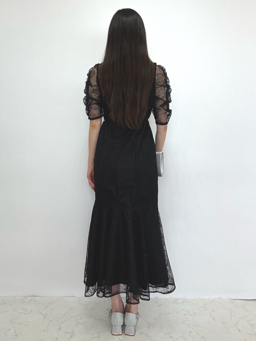 ブラック系のドレス、シルバー系のクラッチバッグ、シルバー系のパンプスを着用したレディースの秋コーディネートの3枚目の写真