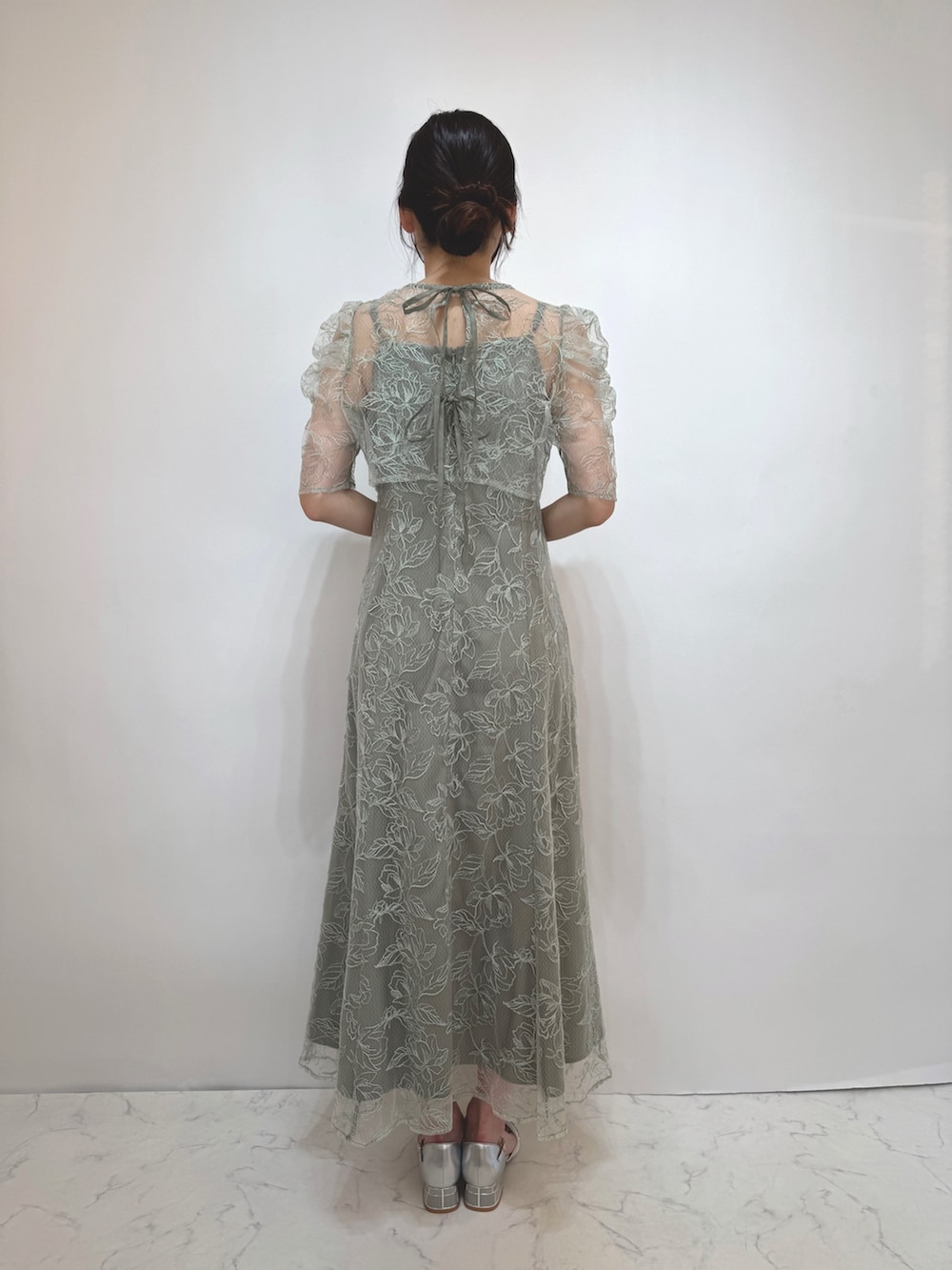 グリーン系のドレス、シルバー系のパンプスを着用したレディースの冬コーディネートの3枚目の写真