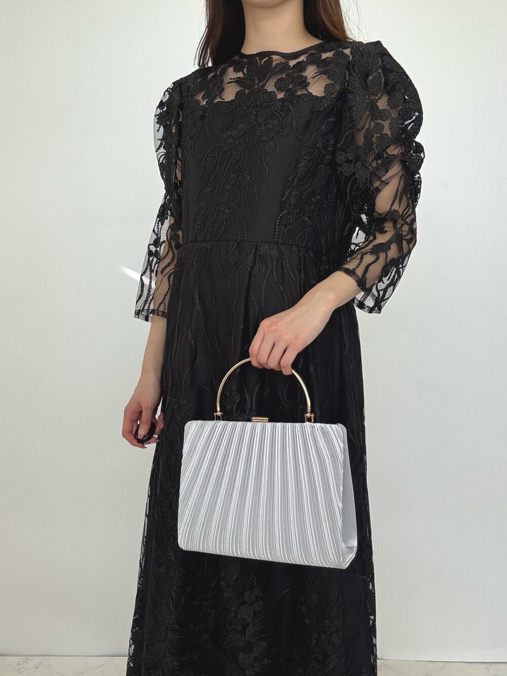 ブラック系のドレス、シルバー系のクラッチバッグ、シルバー系のパンプスを着用したレディースの秋コーディネートの5枚目の写真