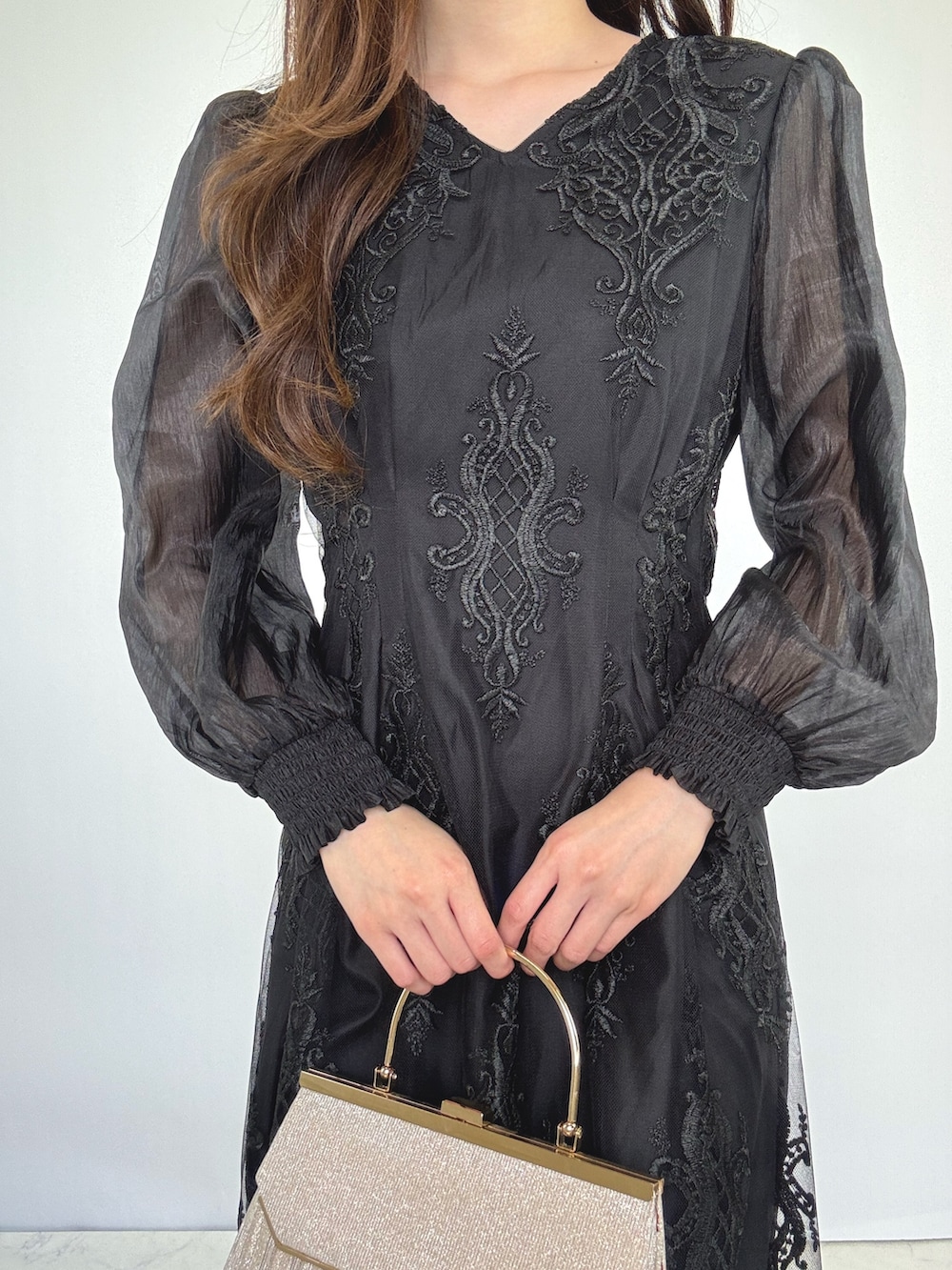 ベージュ系のクラッチバッグ、ベージュ系のパンプス、ブラック系のドレスを着用したレディースの秋コーディネートの3枚目の写真