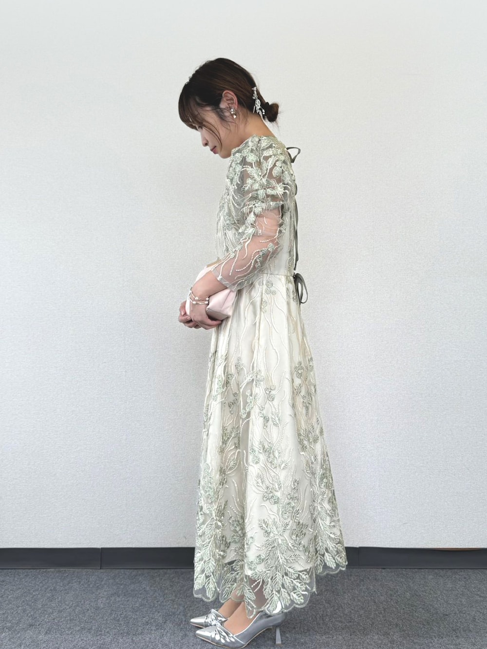 ブラック系のクラッチバッグ、グリーン系のドレス、シルバー系のパンプスを着用したレディースの冬コーディネートの2枚目の写真