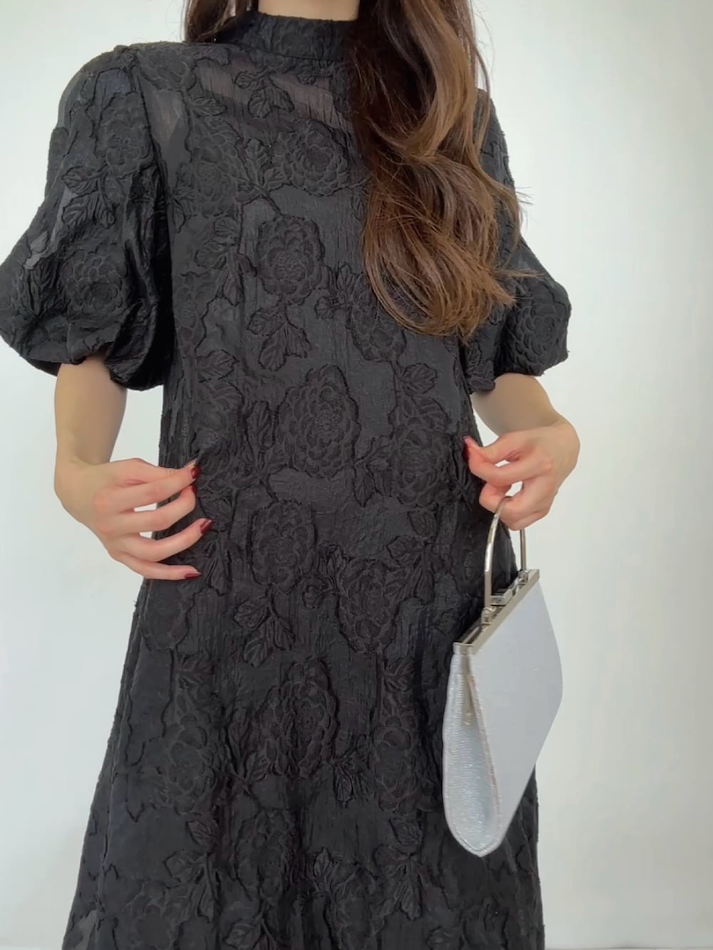 シルバー系のクラッチバッグ、ブラック系のドレス、シルバー系のパンプスを着用したレディースの秋コーディネートの4枚目の写真