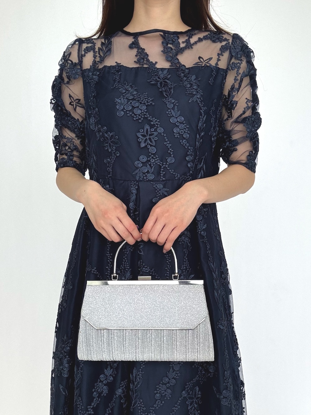 ブルー系のドレス、シルバー系のパンプス、シルバー系のクラッチバッグを着用したレディースの秋コーディネートの2枚目の写真